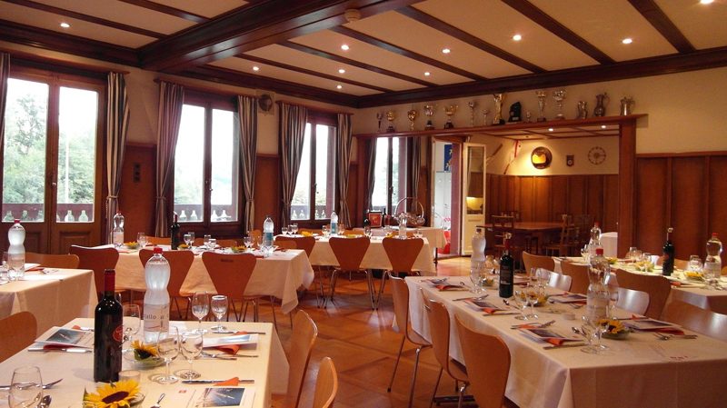 Illustration: A large dining room with set tables and wooden ceiling beams