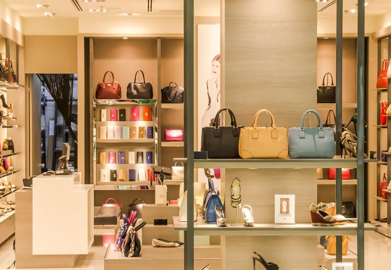 Illustration: A bright modern boutique with shelves displaying numerous designer handbags