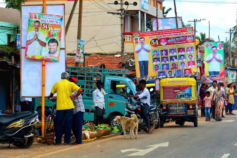 Illustration: A busy street with political posters on poles and a stray dog