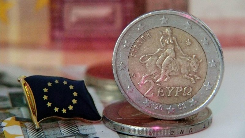 Illustration: A two euro coin next to an EU flag badge