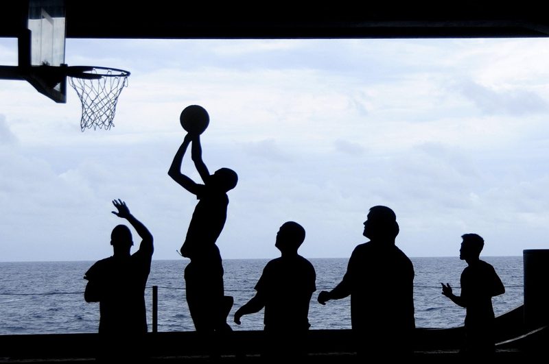 Illustration: Silhouettes of people playing basketball with the ocean behind
