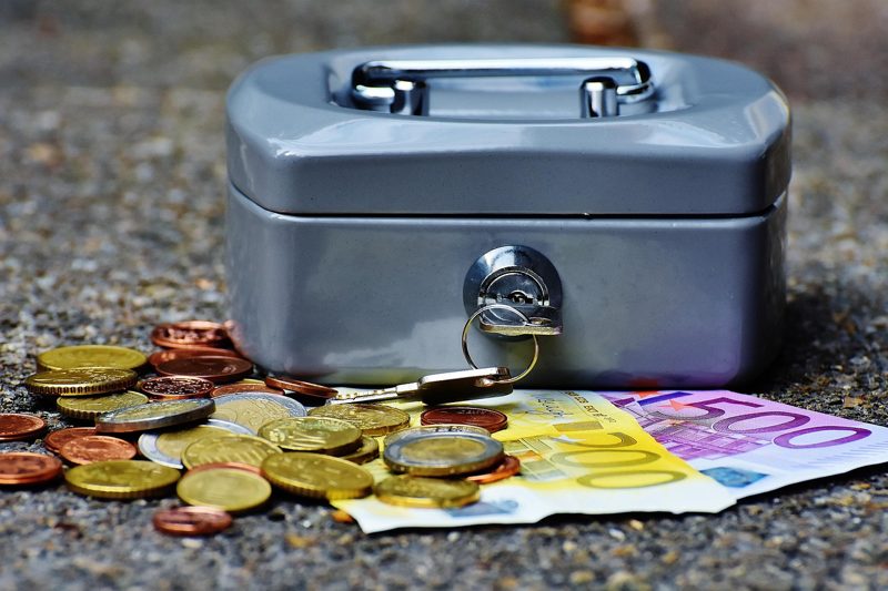 Illustration: A metal cash box with paper money and coins around it