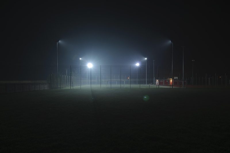 Illustration: An empty football pitch lit by floodlights at night