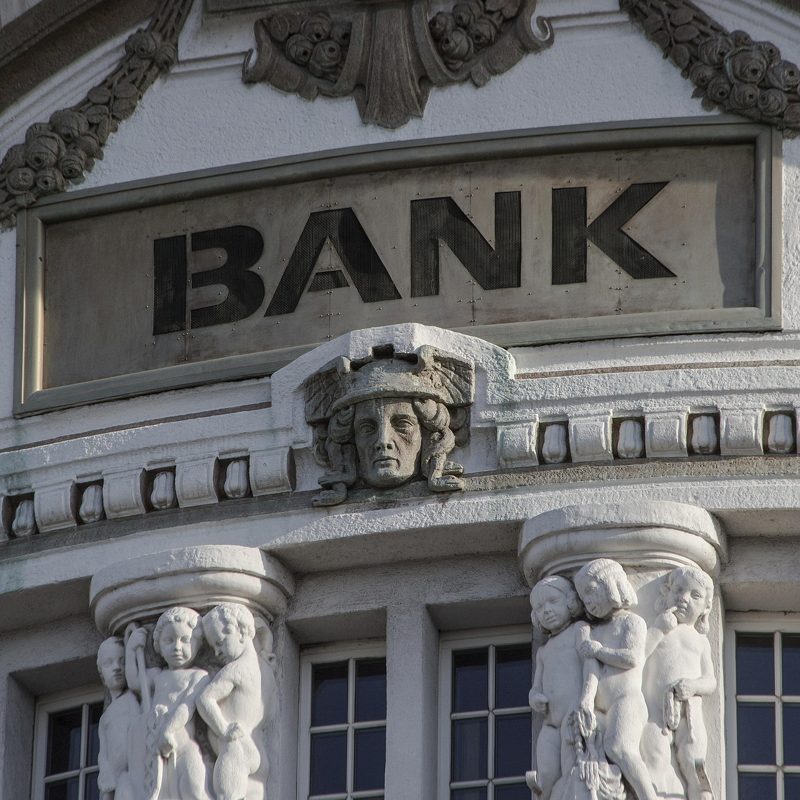 Illustration: An ornate stone building with the word "BANK" inscribed above
