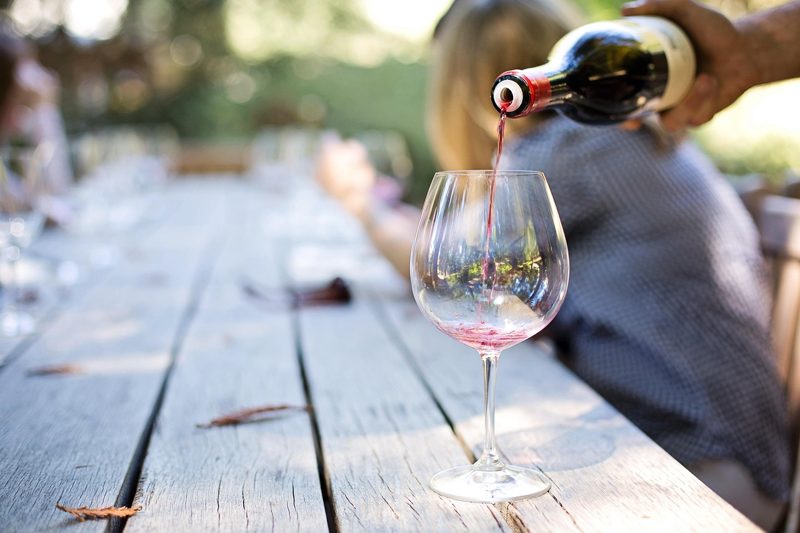 Illustration: Someone pouring wine into a glass on an outdoor table