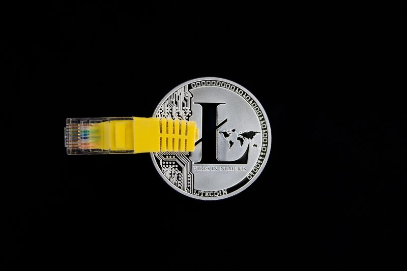 Illustration: A litecoin coin with a yellow ethernet cable plugged in
