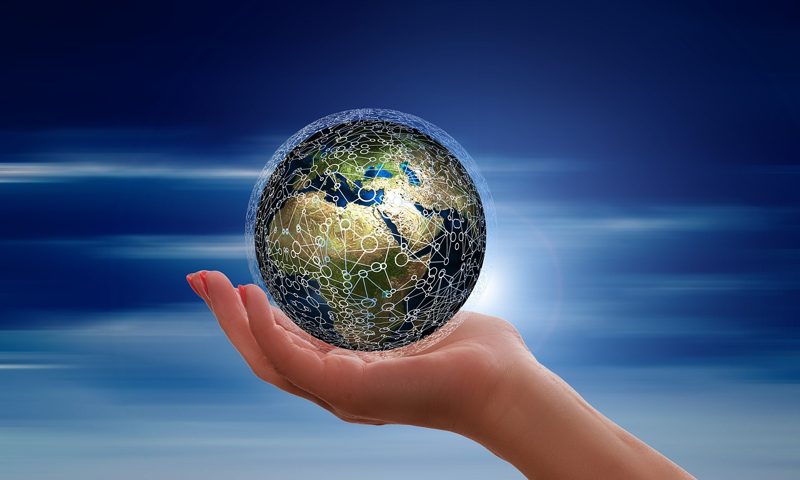 Illustration: A hand holding a digital globe with a sky background