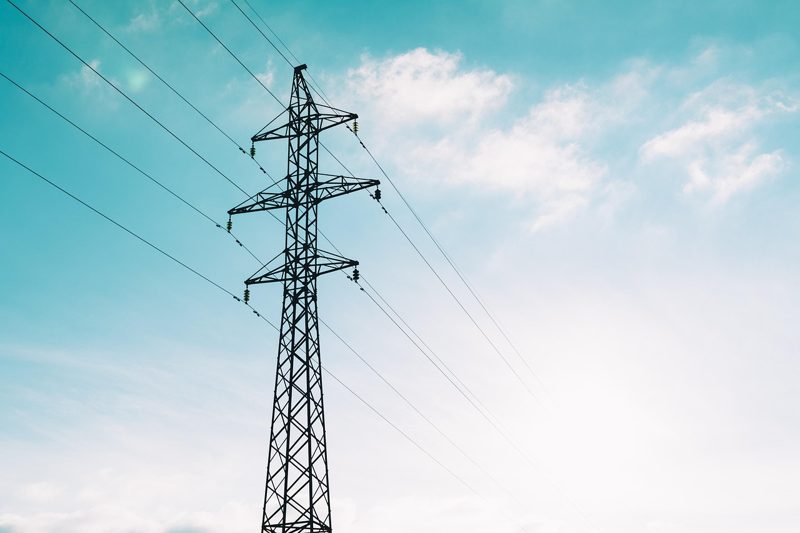 Illustration: A tall power pylon against a bright blue sky