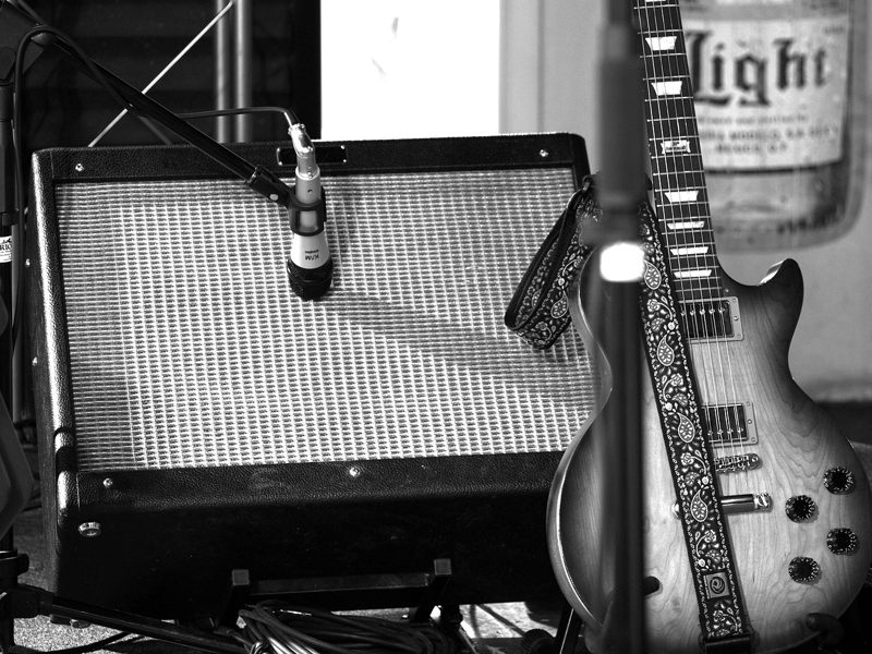 Illustration: An electric guitar leaning against a guitar amplifier with a microphone