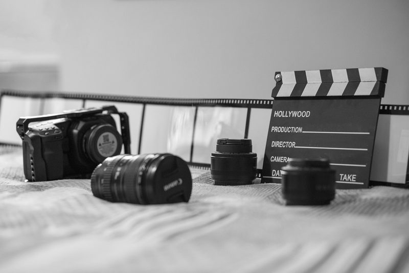 Illustration: A movie clapperboard and professional cameras lenses on a bed