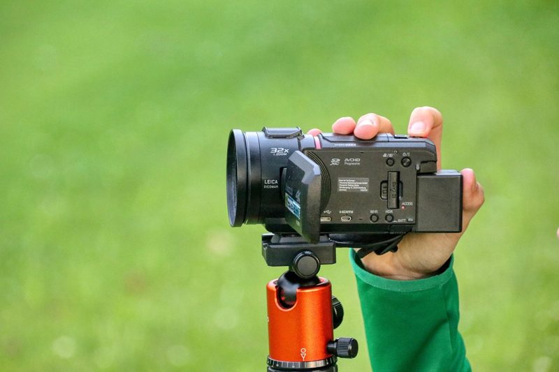 Illustration: A person filming with a video camera mounted on a tripod