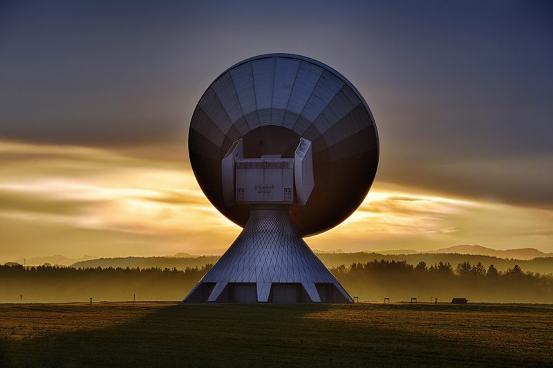 Illustration: A large satellite dish antenna outdoors against a sunset sky