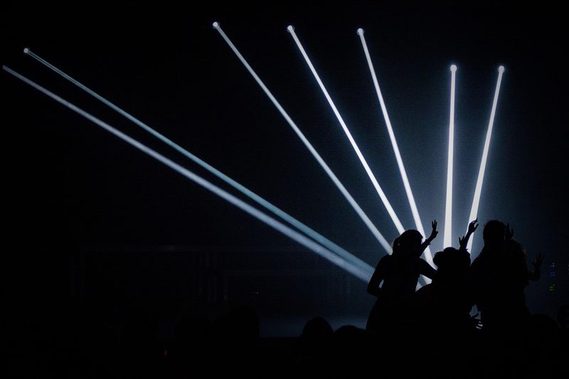 Illustration: Silhouetted people at a concert enjoying the show under stage lights