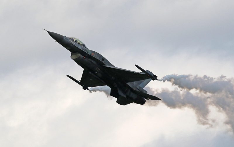 Illustration: A military jet fighter in flight leaving smoke trails behind
