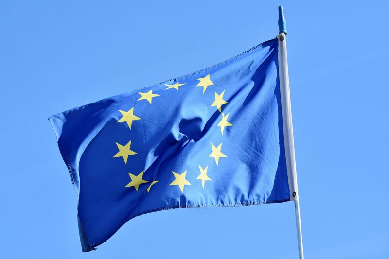 Illustration: The flag of Europe waving against a clear blue sky