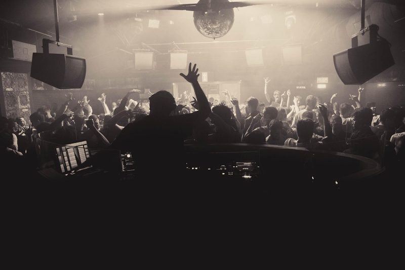 Illustration: A crowded nightclub with a dj performing on stage