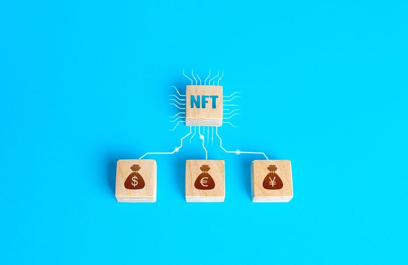Illustration: A wooden block labeled NFT connected to currency bag blocks