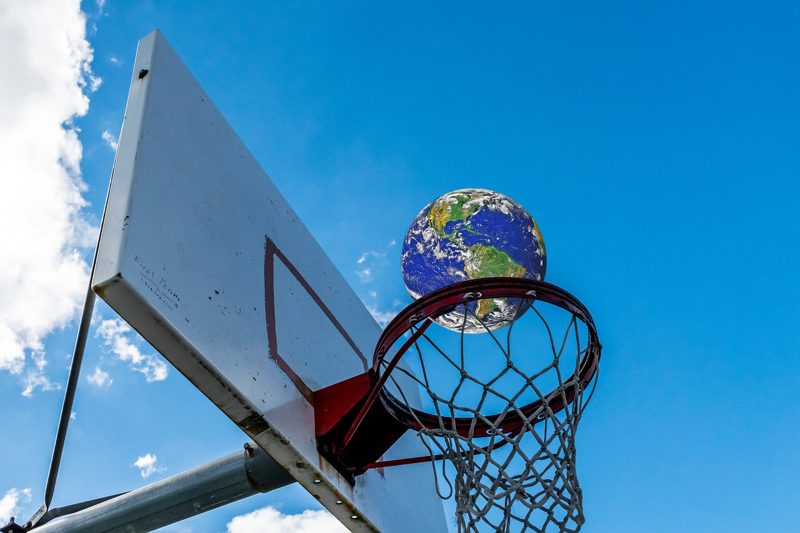 Illustration: The Earth is passing through a basketball hoop in a clear sky