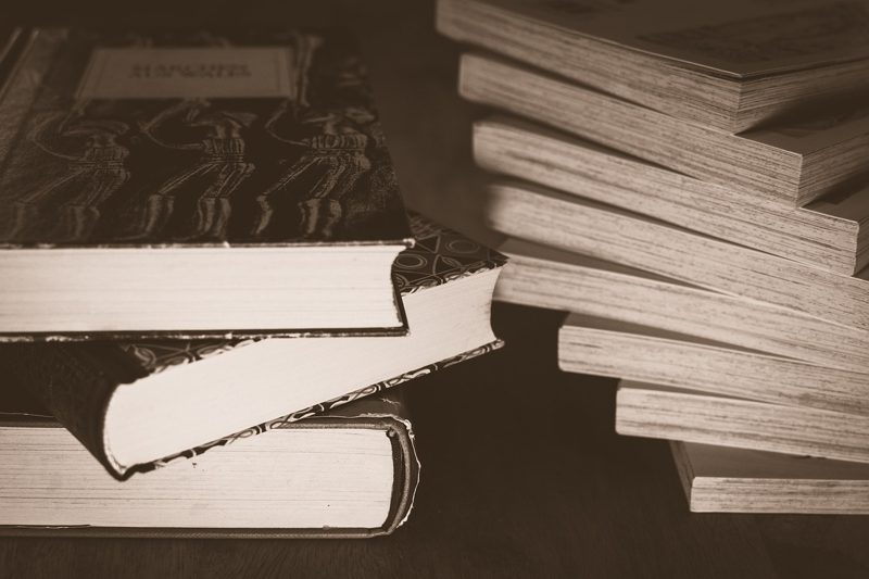 Illustration: Two stacks of old books sit on a dark wooden table