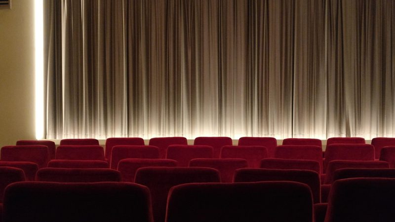 Illustration: Red seats in front of a closed silver theatre curtain