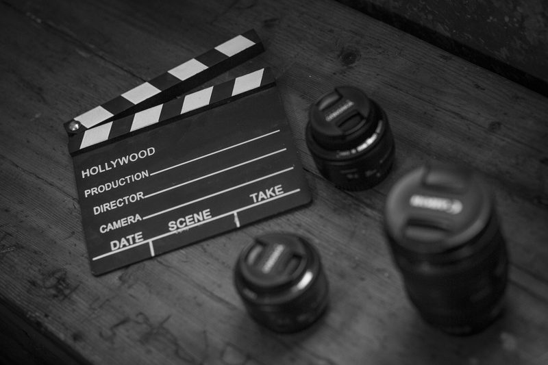 Illustration: A black and white clapperboard with three camera lenses on wood