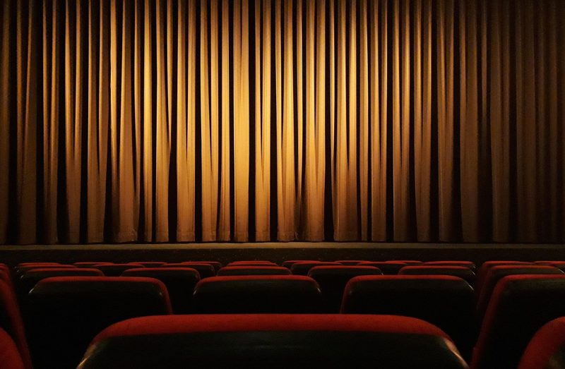 Illustration: Red seats in front of a closed golden theatre curtain