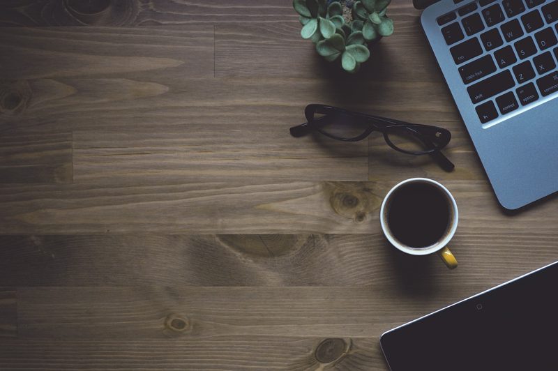 Illustration: Laptop, coffee cup, glasses, and a plant on a wooden desk