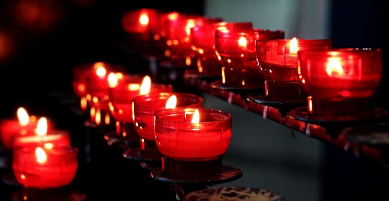 Illustration: A row of red votive candles burning in a church