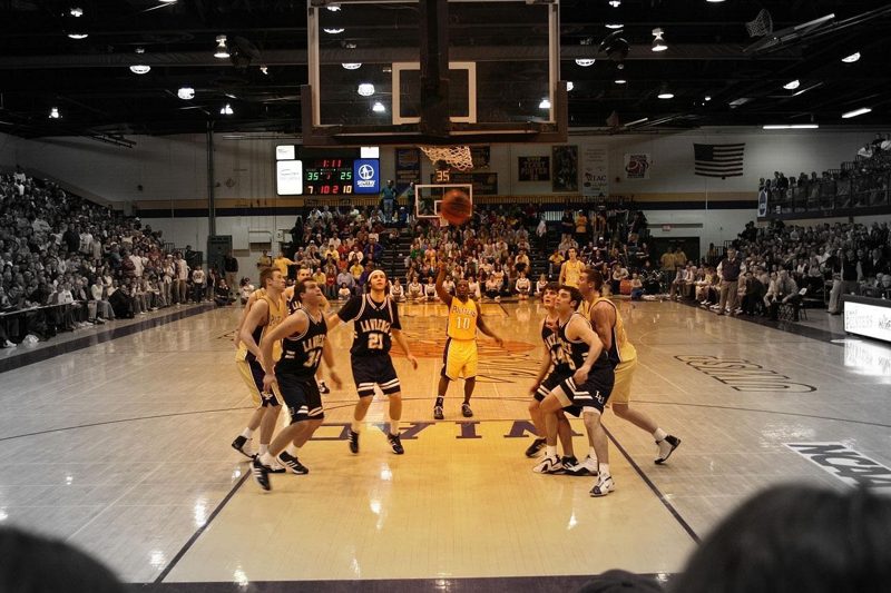 Illustration: Basketball players on a court with spectators in the background