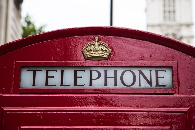 Illustration: A close up view of a red telephone box with a crown