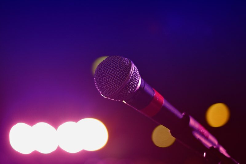 Illustration: A microphone stand on a stage against a colorful background