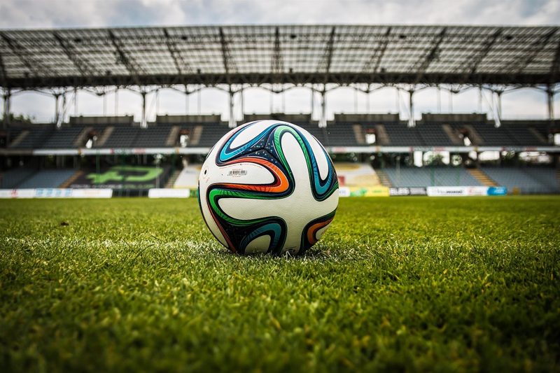 Illustration: A football on the grass in a large stadium