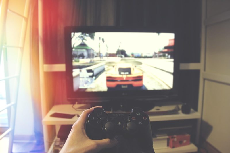 Illustration: A person holding a game controller while playing a racing video game