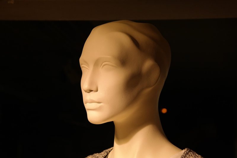 Illustration: The profile of a beige mannequin head against a dark background