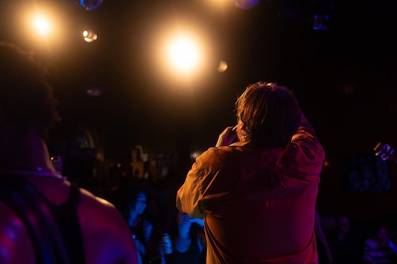 Illustration: A person singing on a dark stage with dramatic lighting