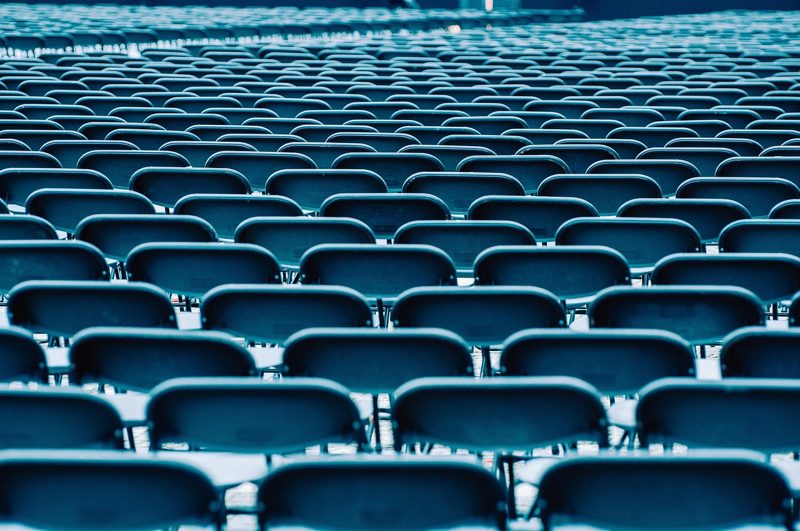 Illustration: A large venue with many empty dark blue chairs