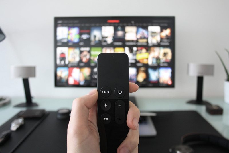 Illustration: A hand holding a remote control in front of a tv