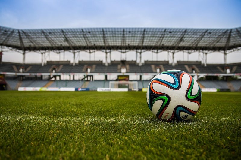 Illustration: A football on the grass of a large stadium