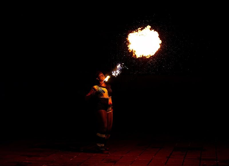 Illustration: A person breathing fire in a dark setting
