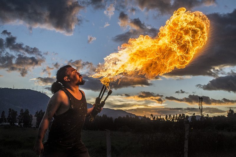 Illustration: A person breathing fire outdoors during the evening