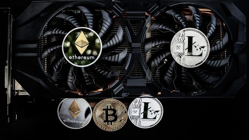 Illustration: A computer graphics card with cryptocurrency coins in front