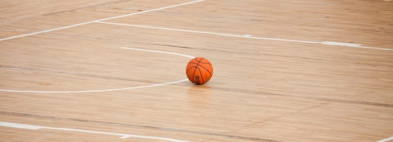 Illustration: A basketball sitting on a light-colored wooden indoor court