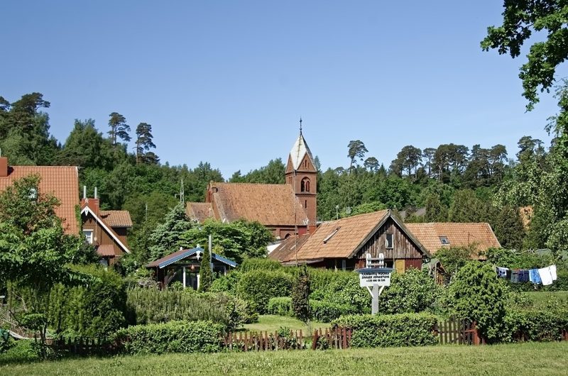 Illustration: A village with small houses, green trees, and a church tower