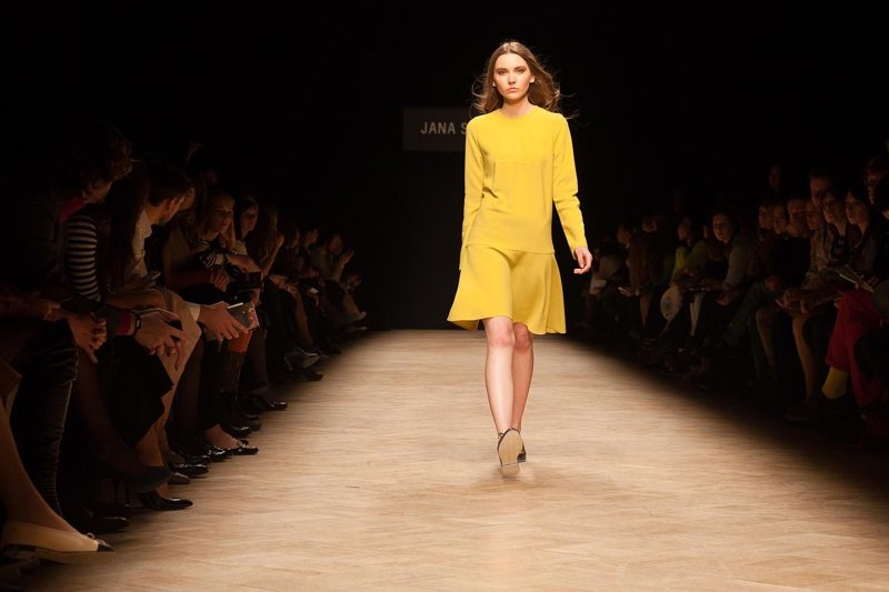 Illustration: A model wearing a yellow dress walking on a runway