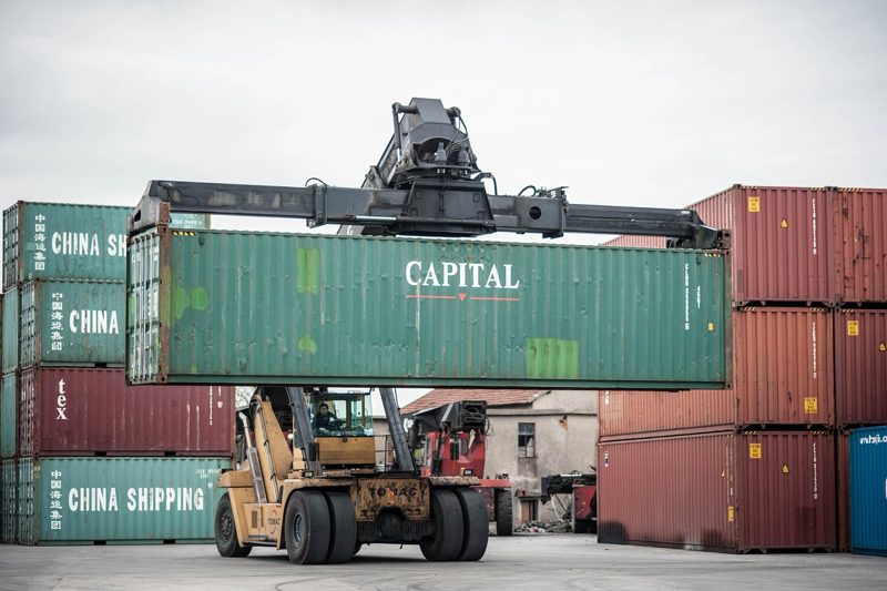 Illustration: A crane lifting a shipping container in an open space