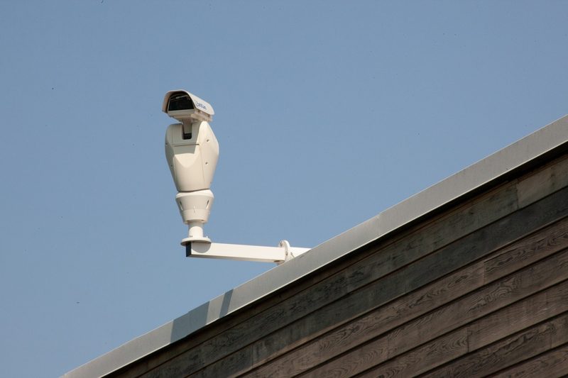 Illustration: A white security camera mounted on a wooden building