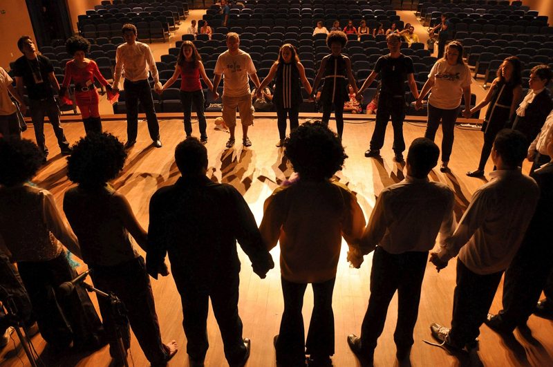 Illustration: A group of people holding hands in a large hall