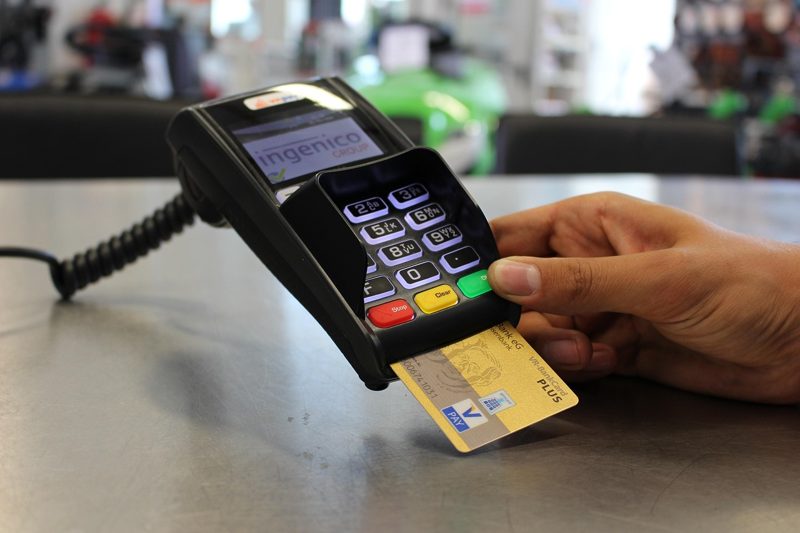 Illustration: A hand swiping a credit card through a payment terminal
