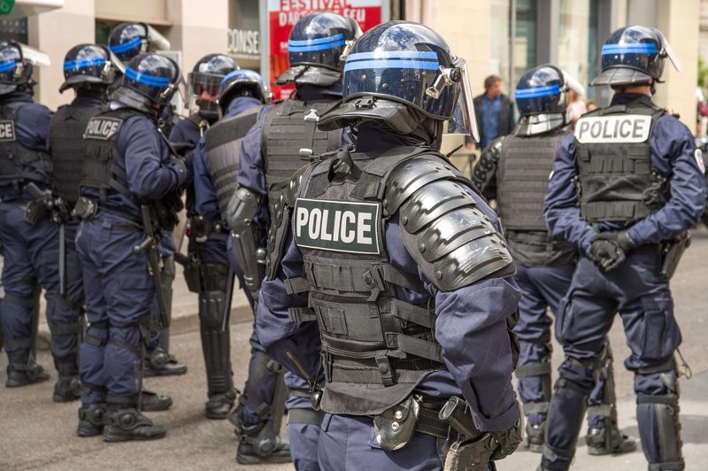 Illustration: A group of police officers stand in full riot gear outdoors