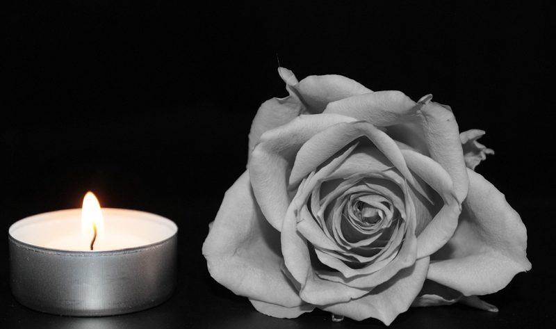 Illustration: A candle burns next to a black and white rose